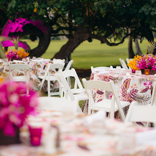 white tables in lawn with vases with fresh flowers placed on them